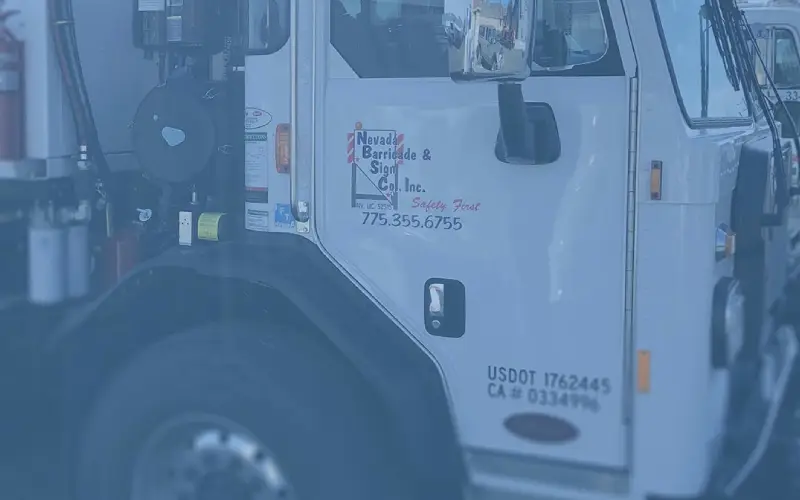 Close-up of Nevada Barricade & Sign Company service truck door with company logo, phone number, and USDOT identification.